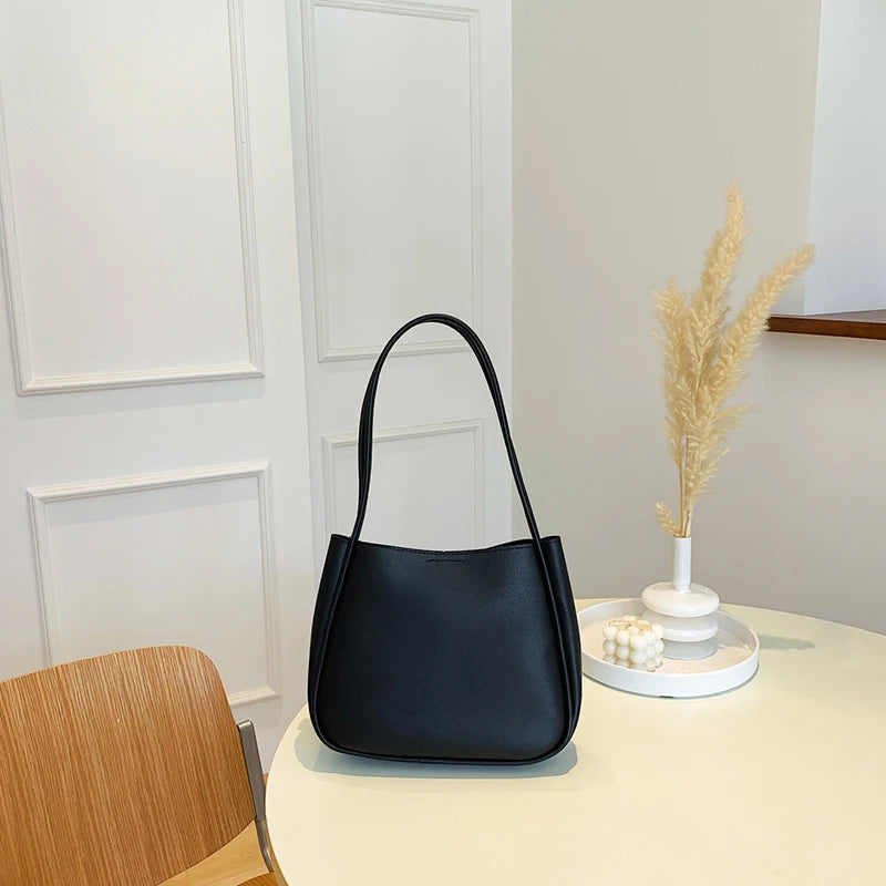 حقيبة كتف أو حقيبة يد صغيرة أنيقة وعملية من الجلد الصناعي، بتصميم عصري وجذاب، مزينة بقلادة على شكل دب.