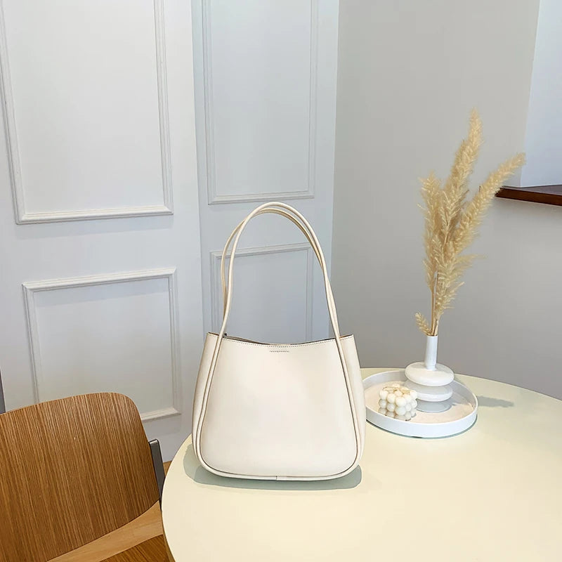 حقيبة كتف أو حقيبة يد صغيرة أنيقة وعملية من الجلد الصناعي، بتصميم عصري وجذاب، مزينة بقلادة على شكل دب.